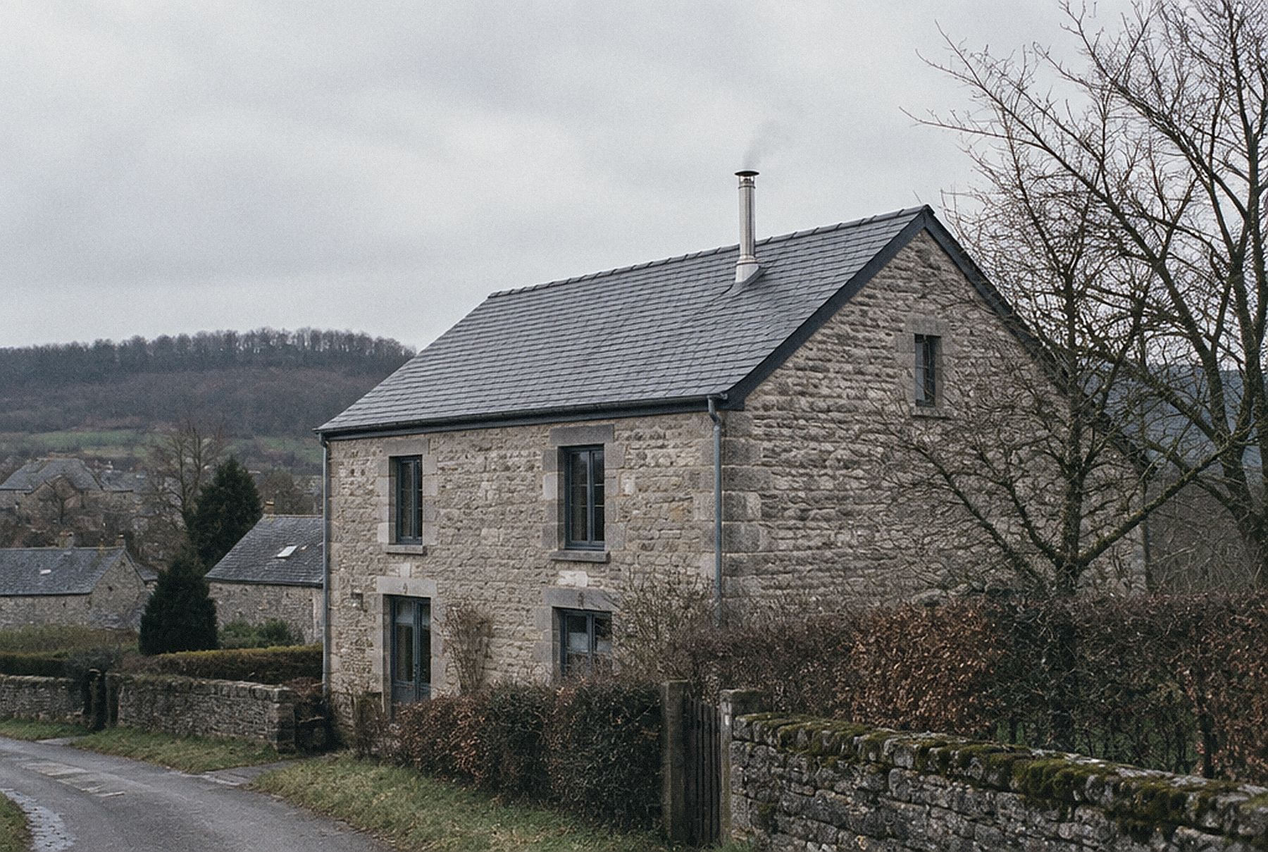 Maison en pierre calcaire avec une sortie de toit inox sur une toiture en ardoise